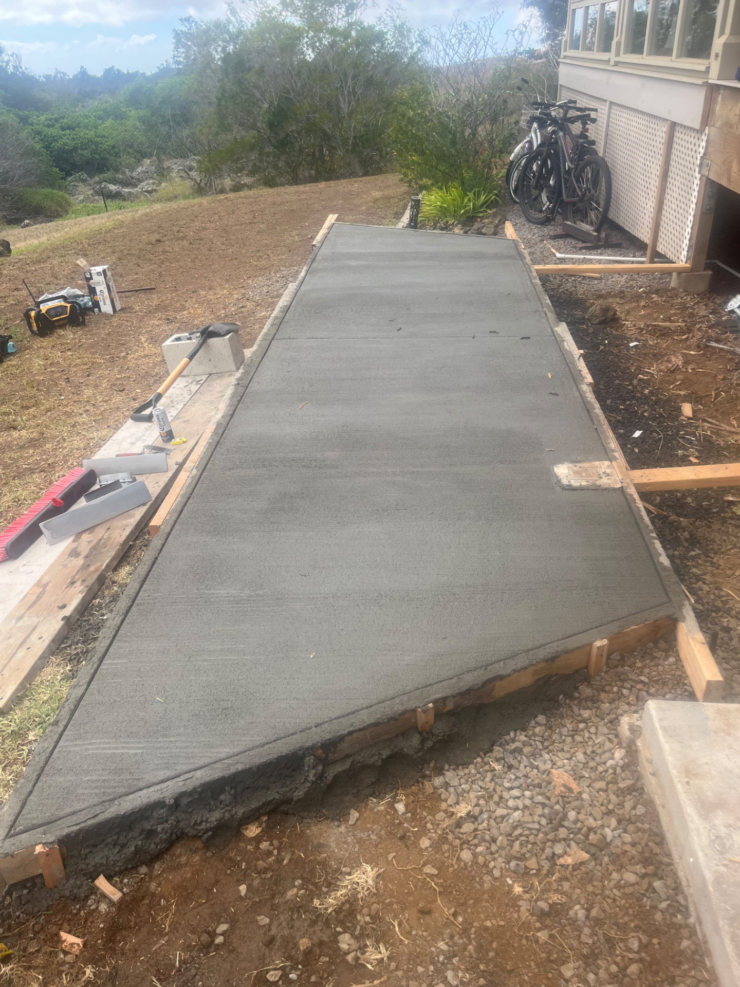 Freshly poured and finished concrete walkway beside a home