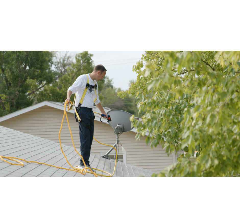 Roof treatment technician working safely on an asphalt shingle roof