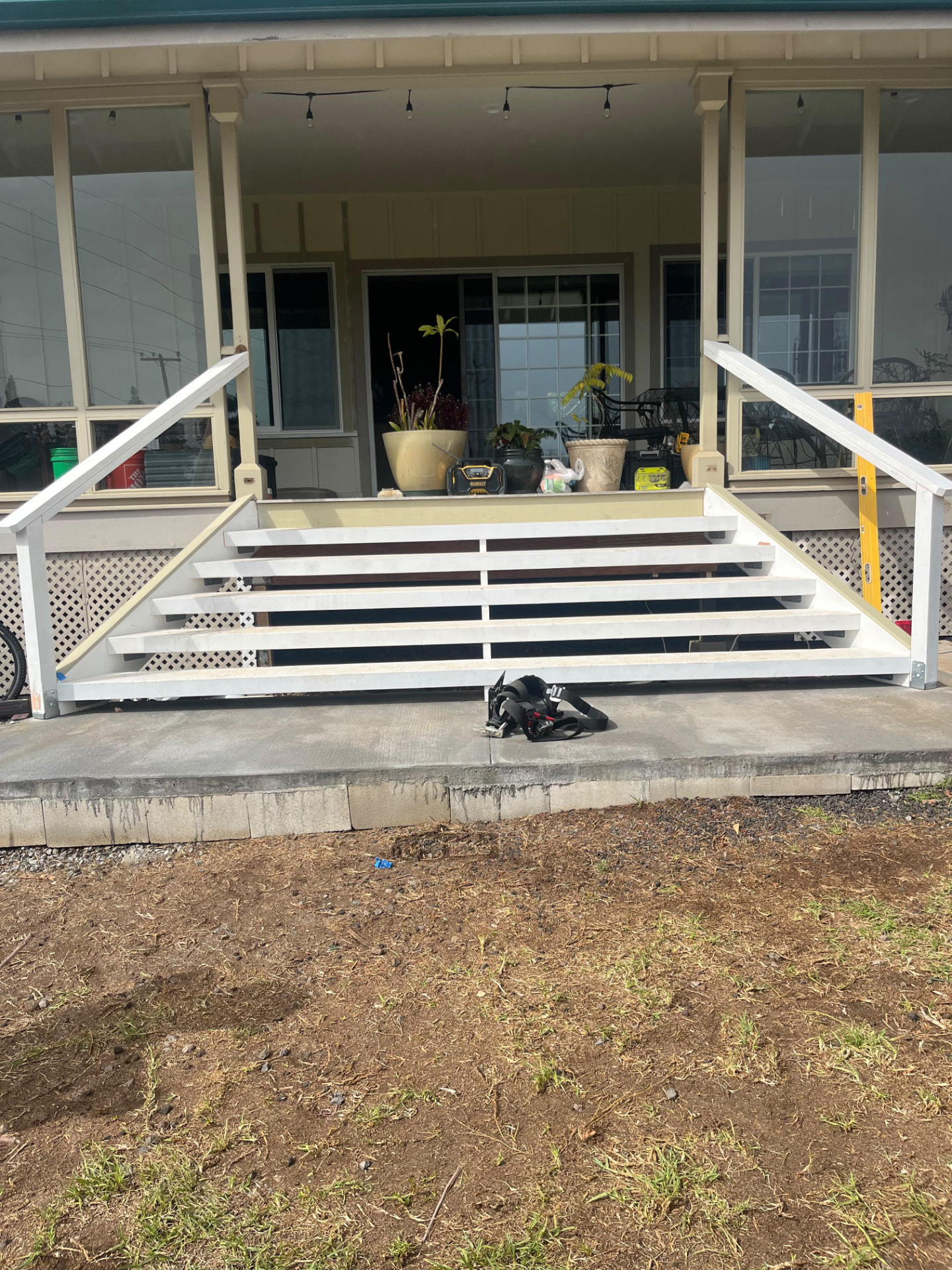 New wide front porch stairs with white handrails on a fresh concrete pad