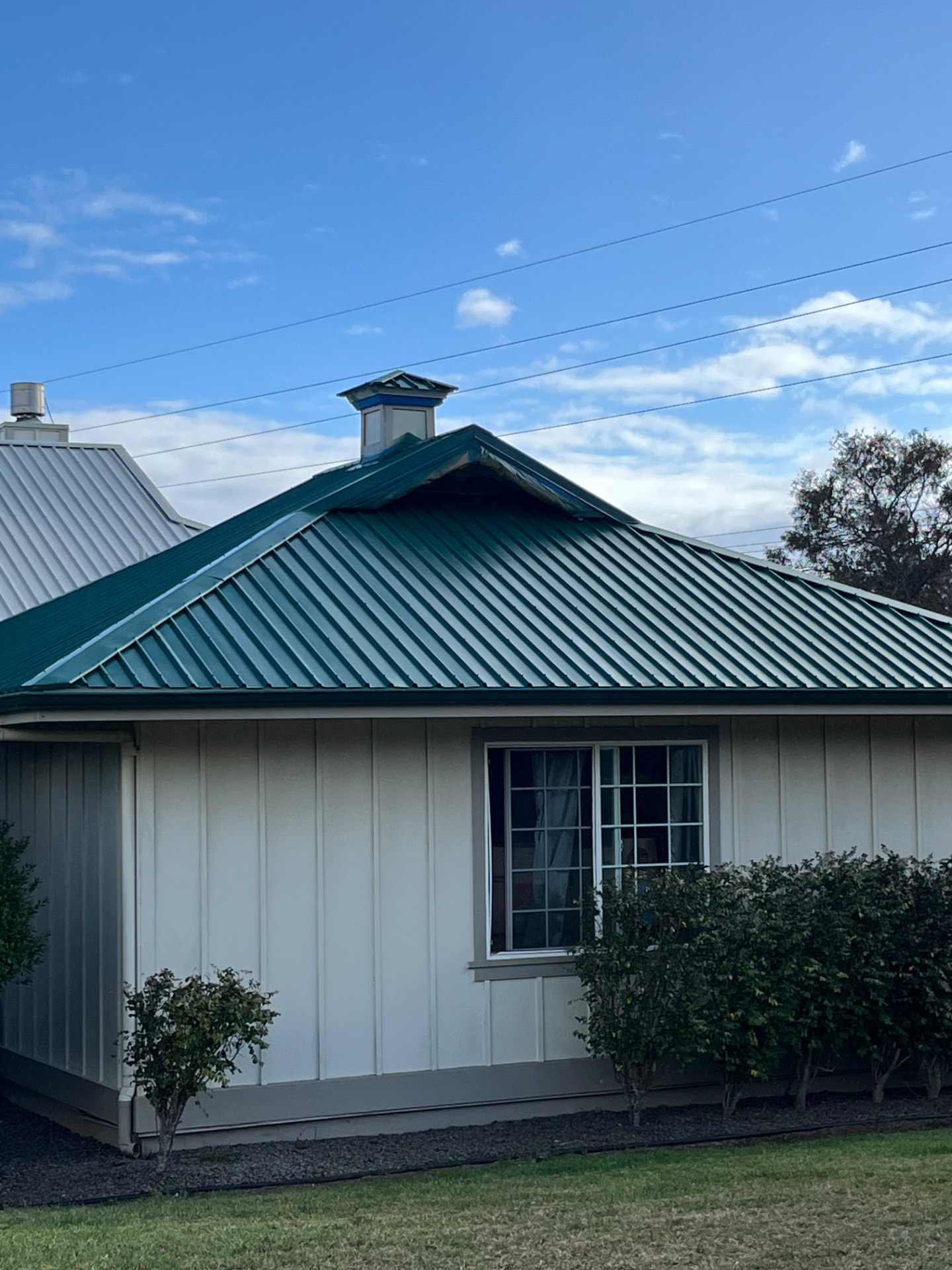 Freshly recoated teal metal roof on a white home