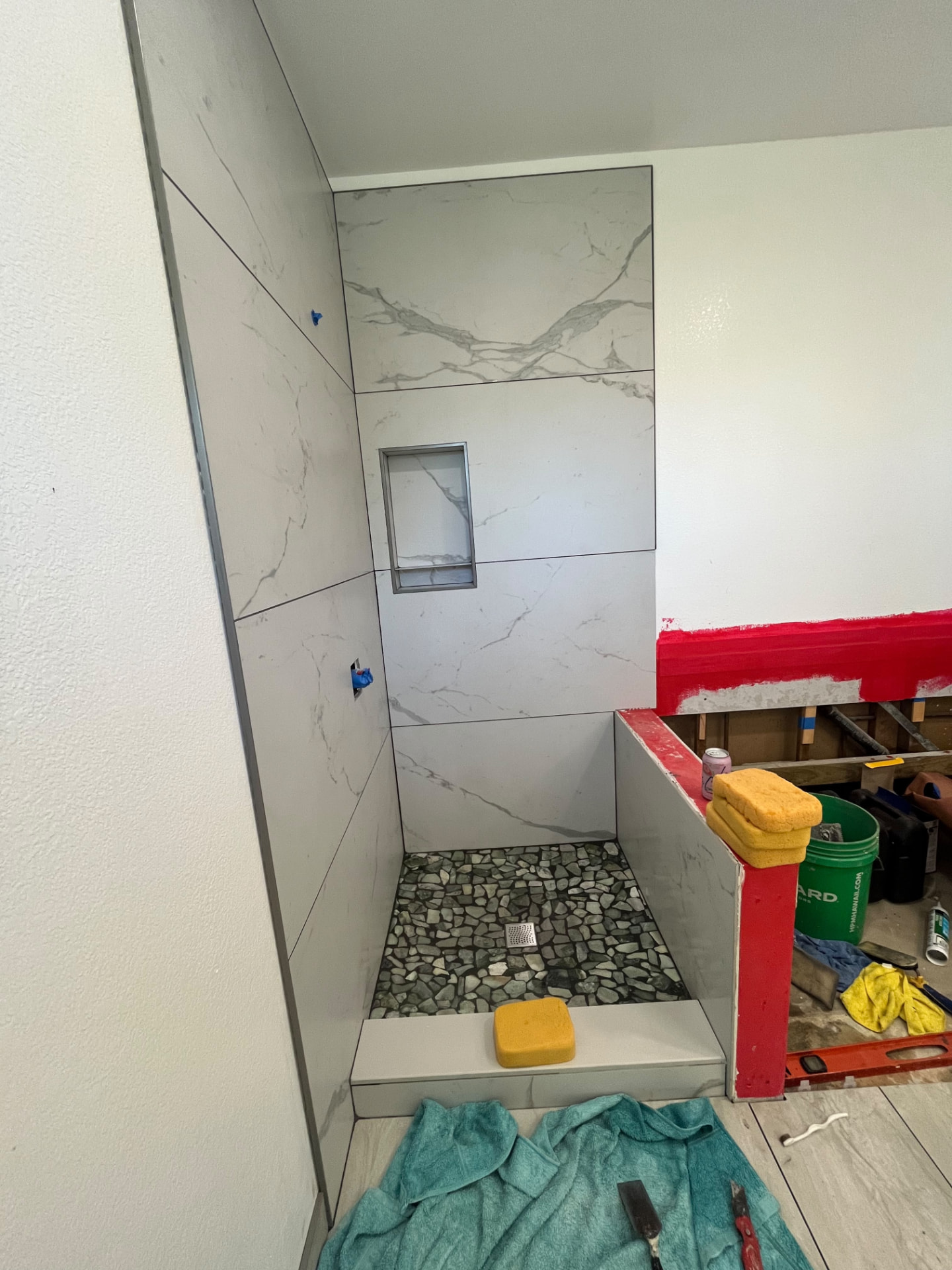 Tiled walk-in shower with recessed niche and pebble stone floor